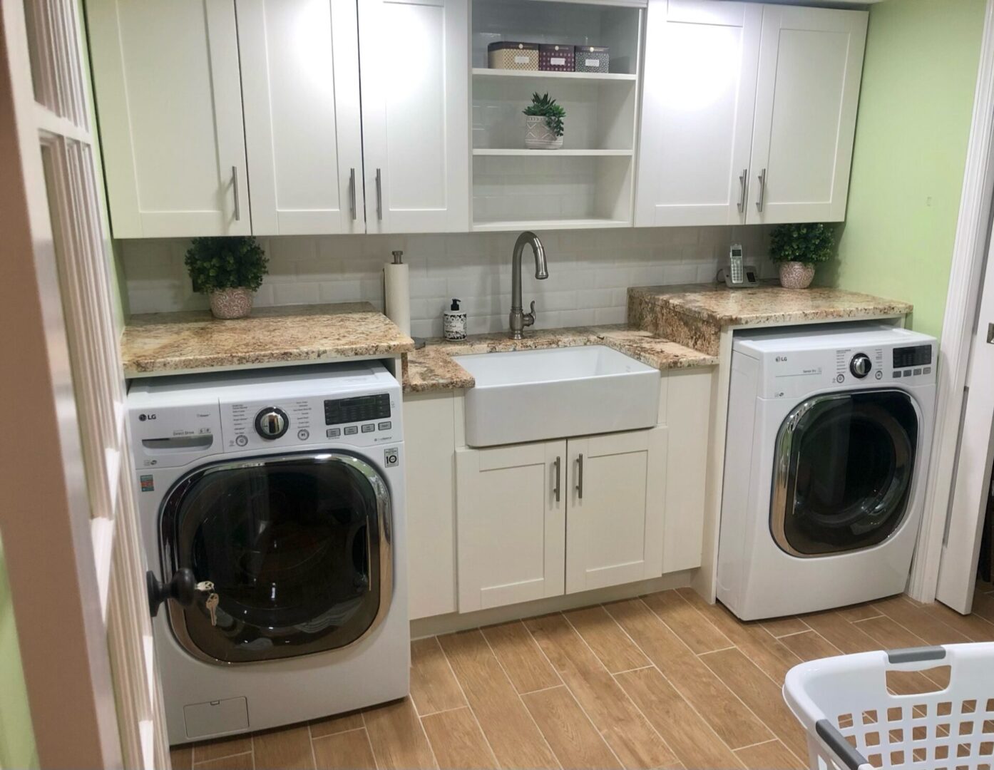 Modern laundry room with washer, dryer, and farmhouse sink.