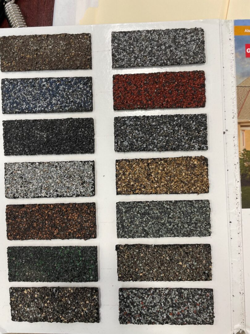 Sample swatches of textured roofing shingles in various colors.