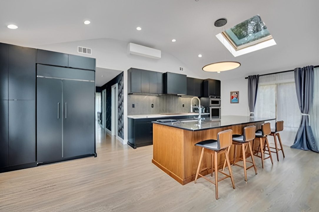 Modern kitchen with black cabinets and wooden island with stools.