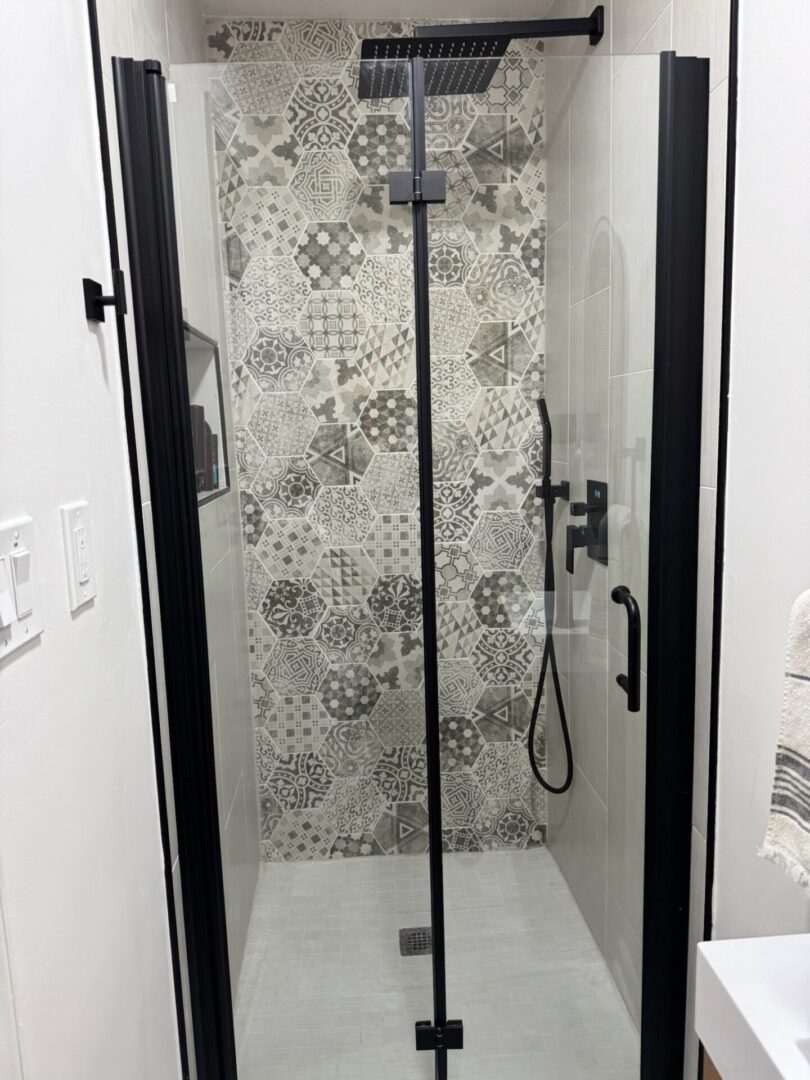 Modern shower with patterned tiles and glass door.