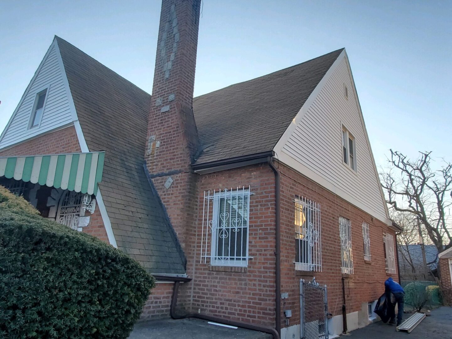 A brick building with a tall chimney and barred window.