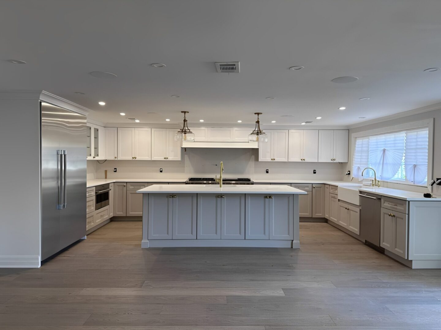Modern white kitchen with a large island and stainless steel appliances.