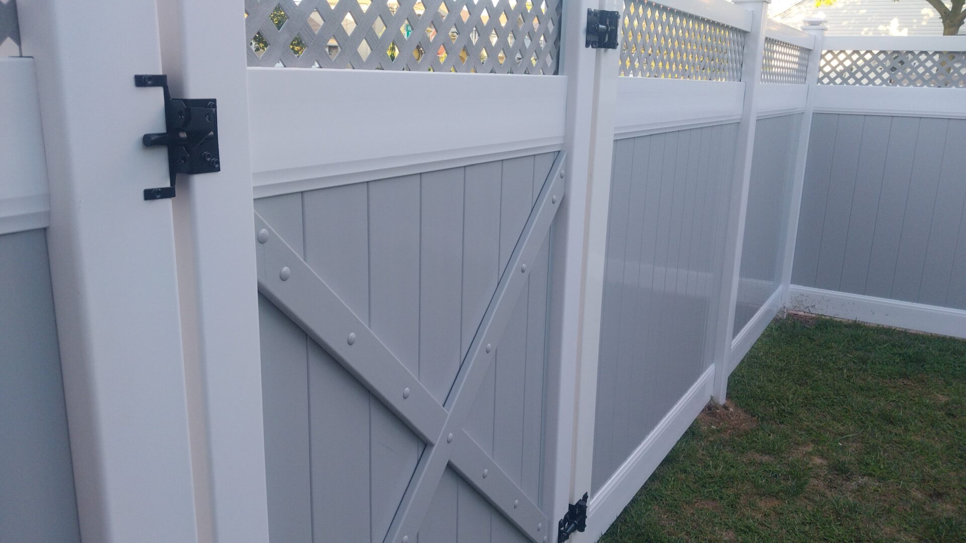 A white vinyl fence with a gate featuring diagonal brace design.