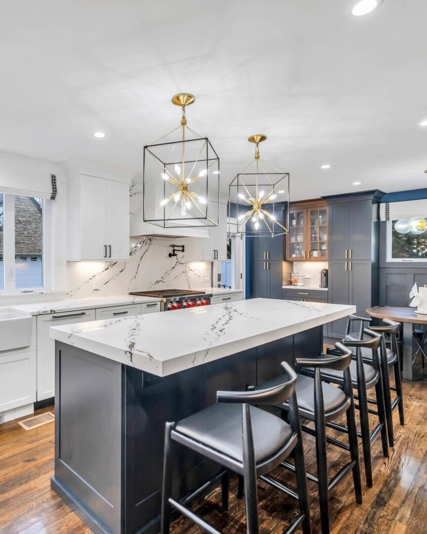 Modern kitchen with marble island and black stools.