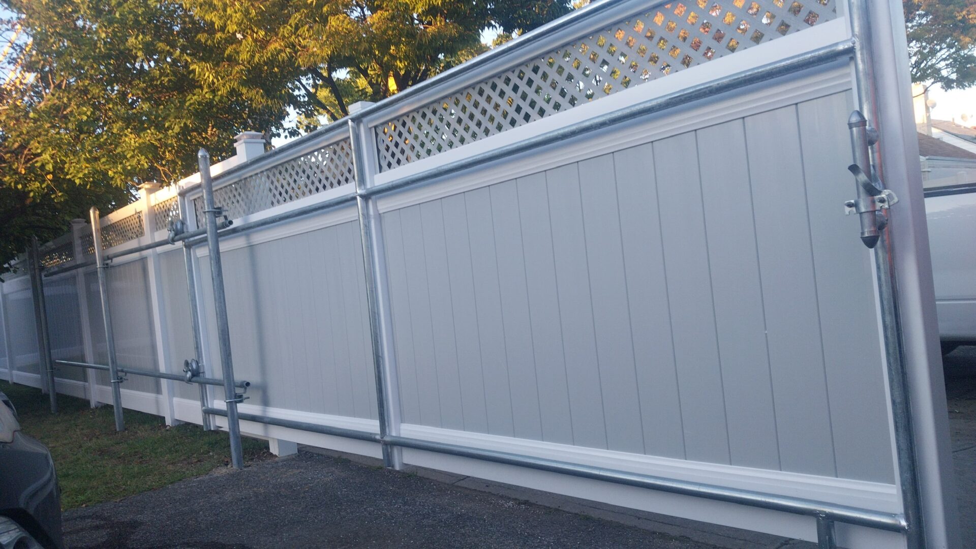 White vinyl privacy fence with lattice top panels outdoors.