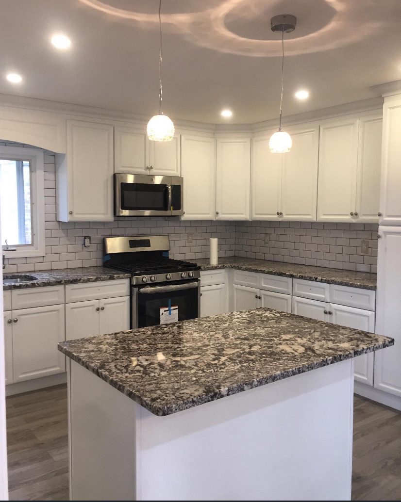 Modern kitchen with granite island and stainless steel appliances.