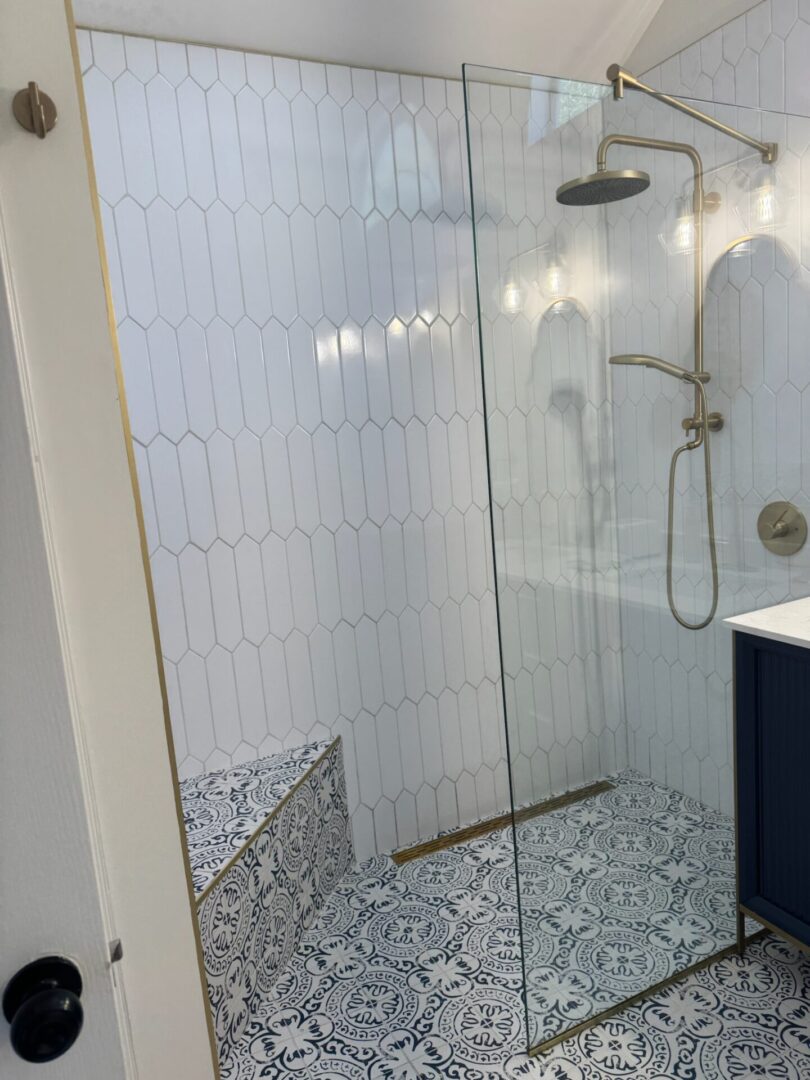 Modern bathroom with glass shower and patterned tiles.