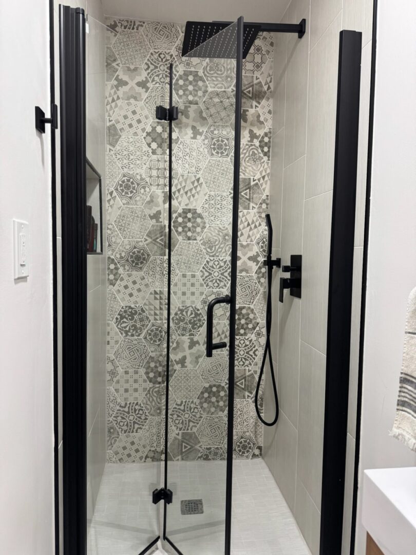Modern glass shower with black trim and patterned frosted design.