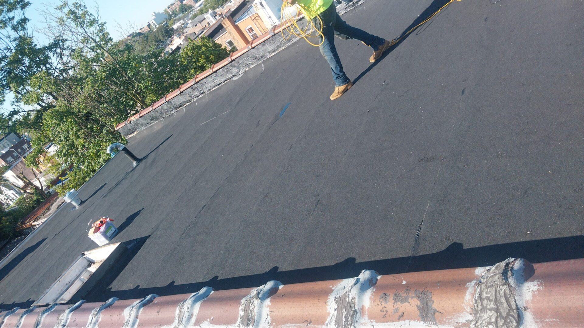 Person walking on a rooftop with visible rooftops and greenery in the background.