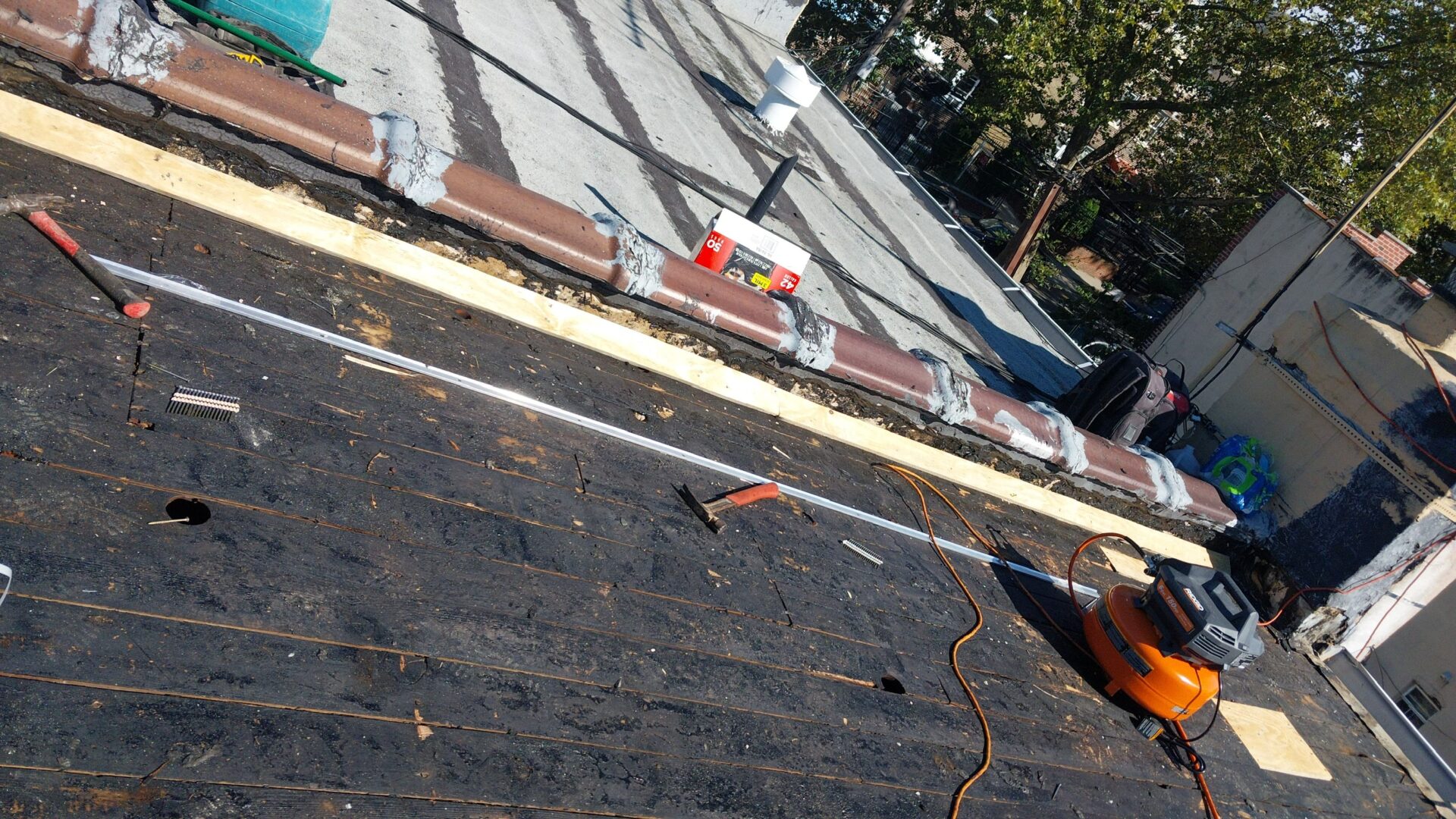 Workers installing roofing materials on a sloped roof under clear skies.