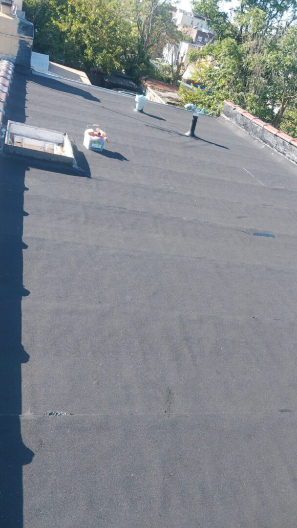 A flat rooftop with a smooth, dark surface and a few scattered objects.