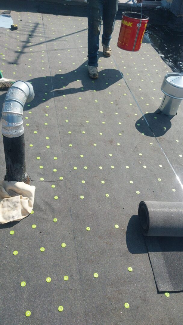 Roof surface with ventilation pipes and yellow markers.